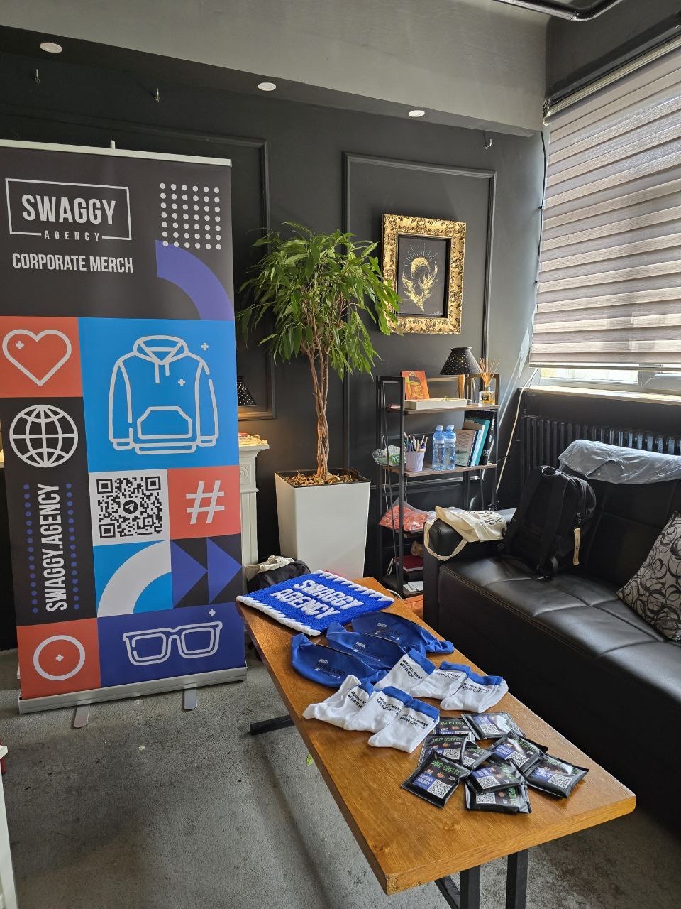 SWAGGY Agency corporate merchandise and event kits displayed with a branded roll-up banner